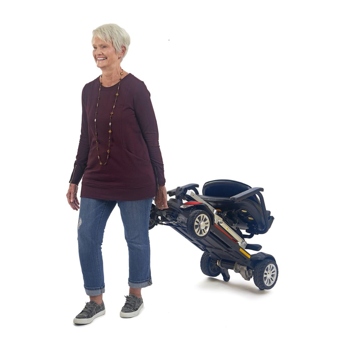 Golden Tech Buzzaround Carry-On Folding Travel Scooter with Travel Battery - in folded state being carried by rider