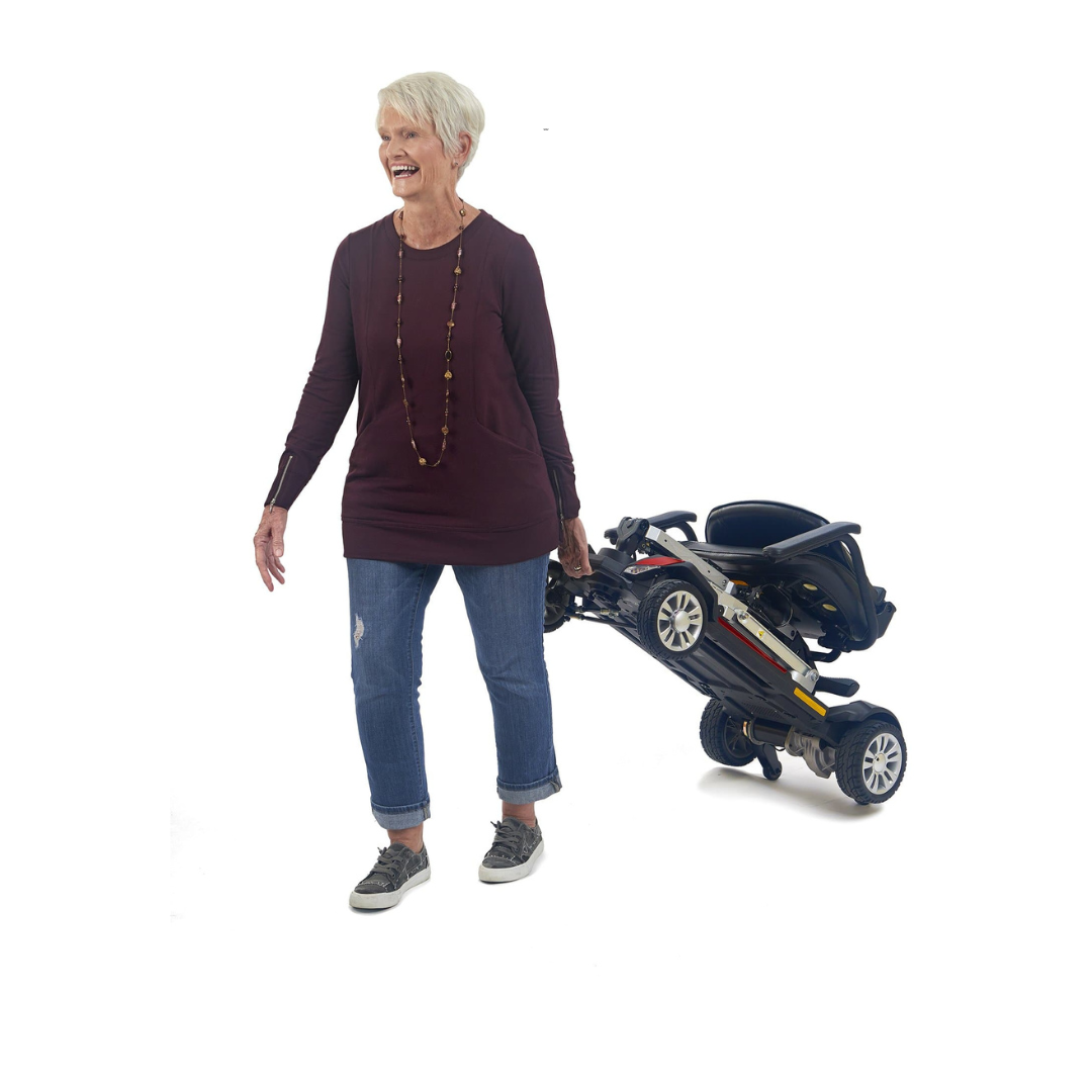 Golden Tech Buzzaround Carry-On Folding Travel Scooter with Travel Battery - in folded state being carried by rider
